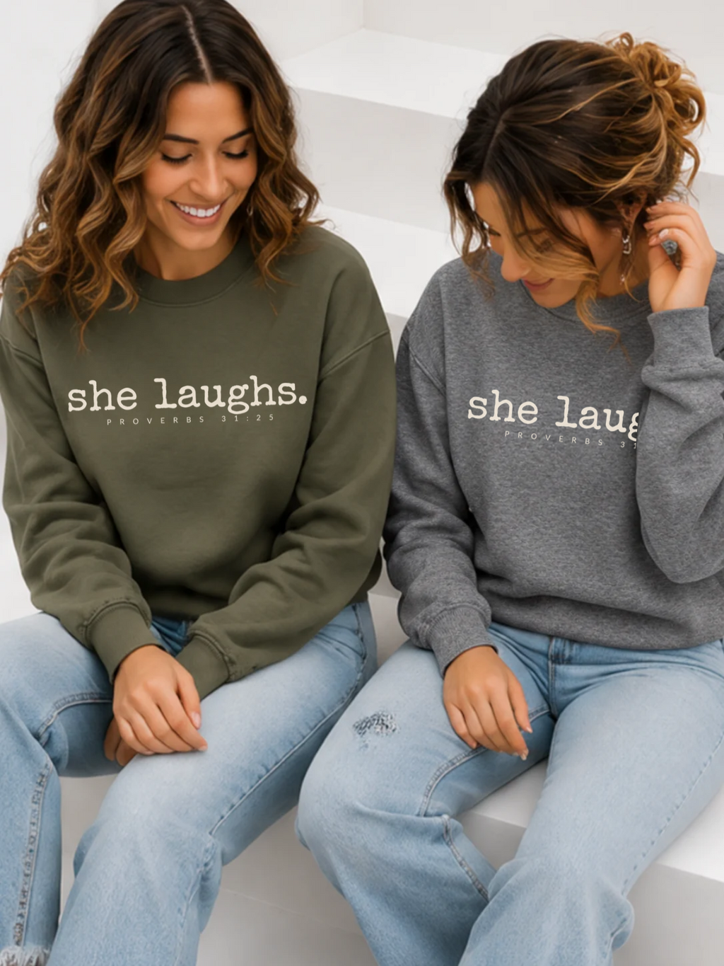 Two women wearing military green and gray She Laughs sweatshirts
