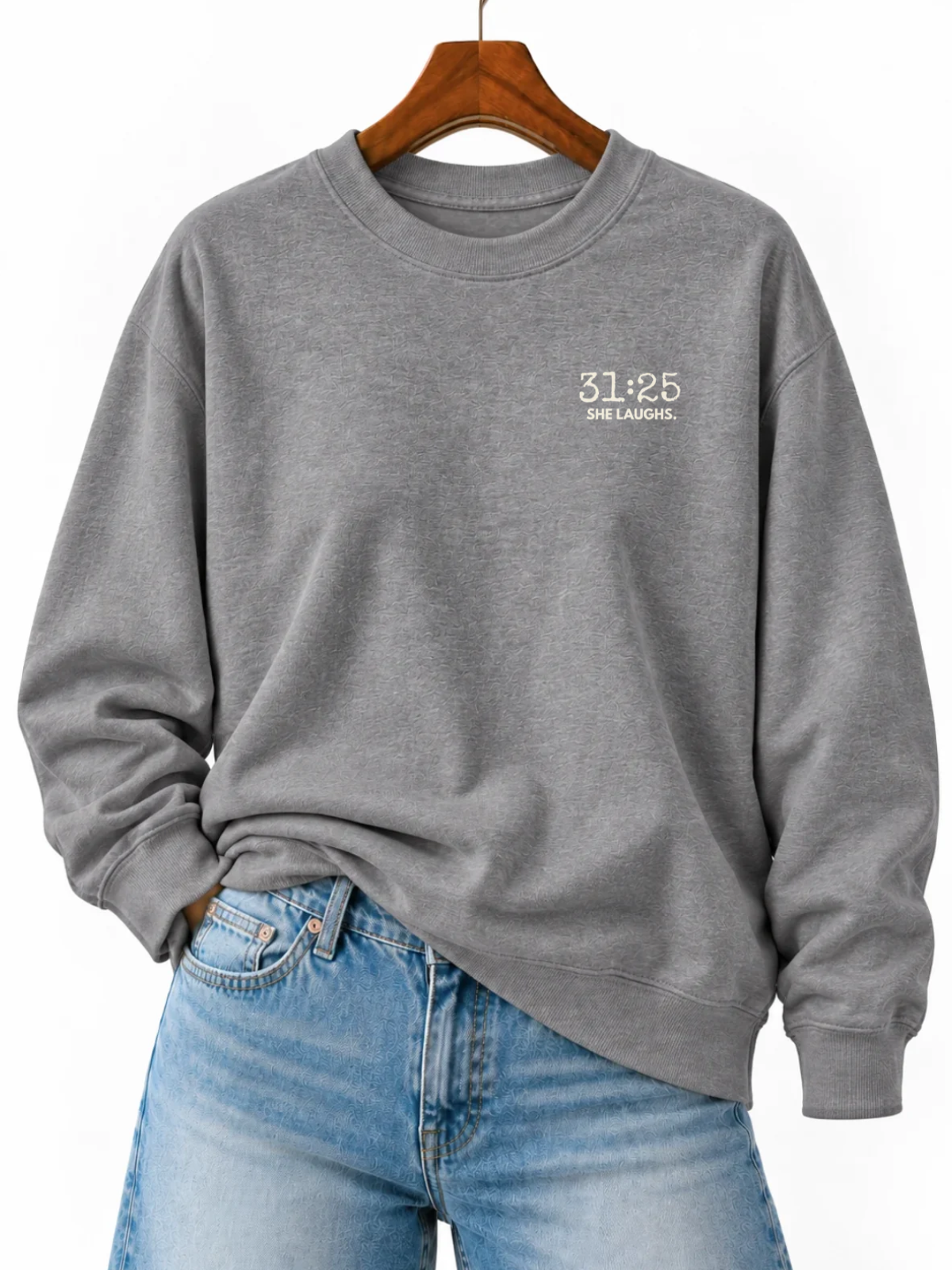 Gray 31:25 Minimal Sweatshirt with small ivory left-chest print, displayed on a wooden hanger and styled with blue jeans.