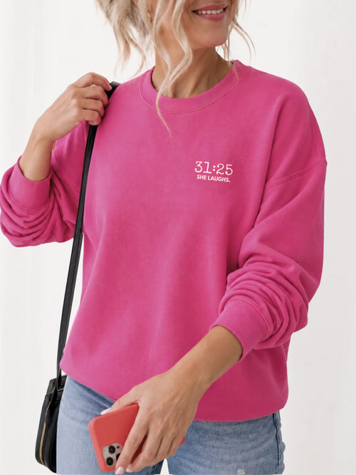 Woman wearing a Heliconia pink 31:25 Minimal Sweatshirt with a small white left-chest design, styled with blue jeans.
