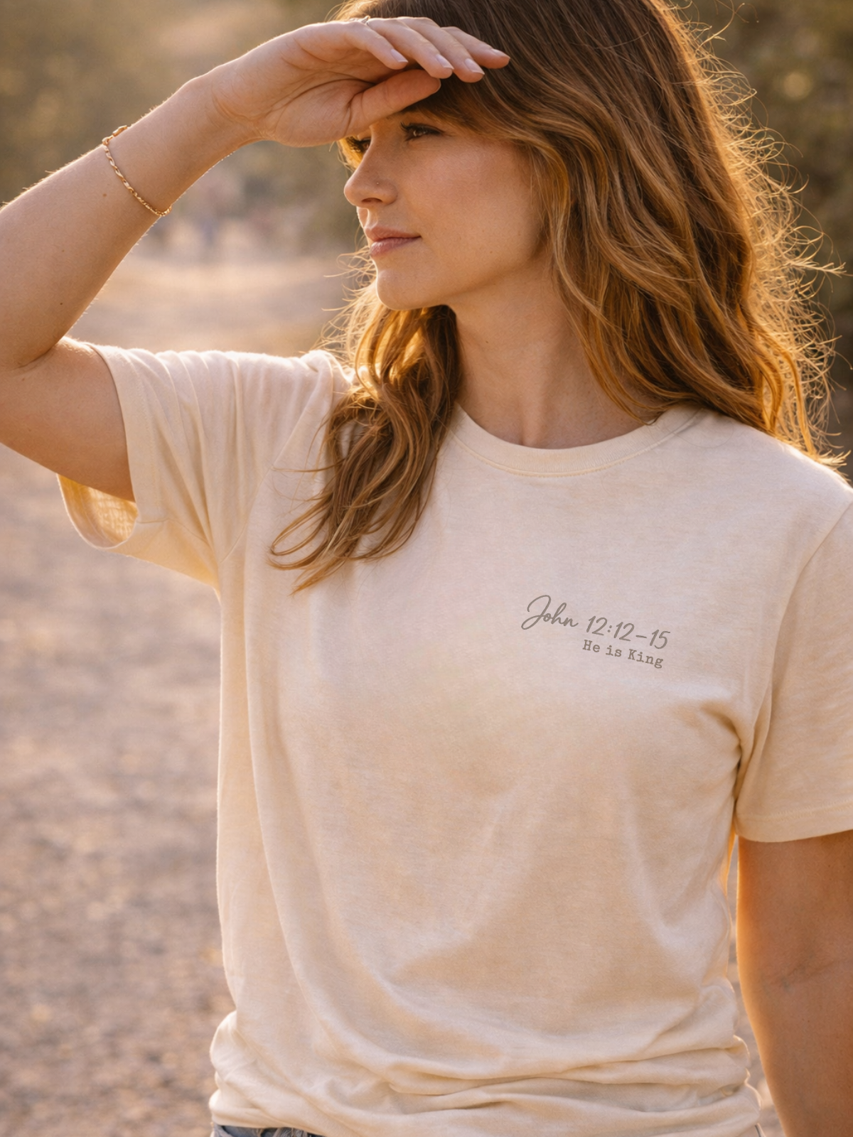 Woman wearing a beige t-shirt with text outdoors John 12:12-15