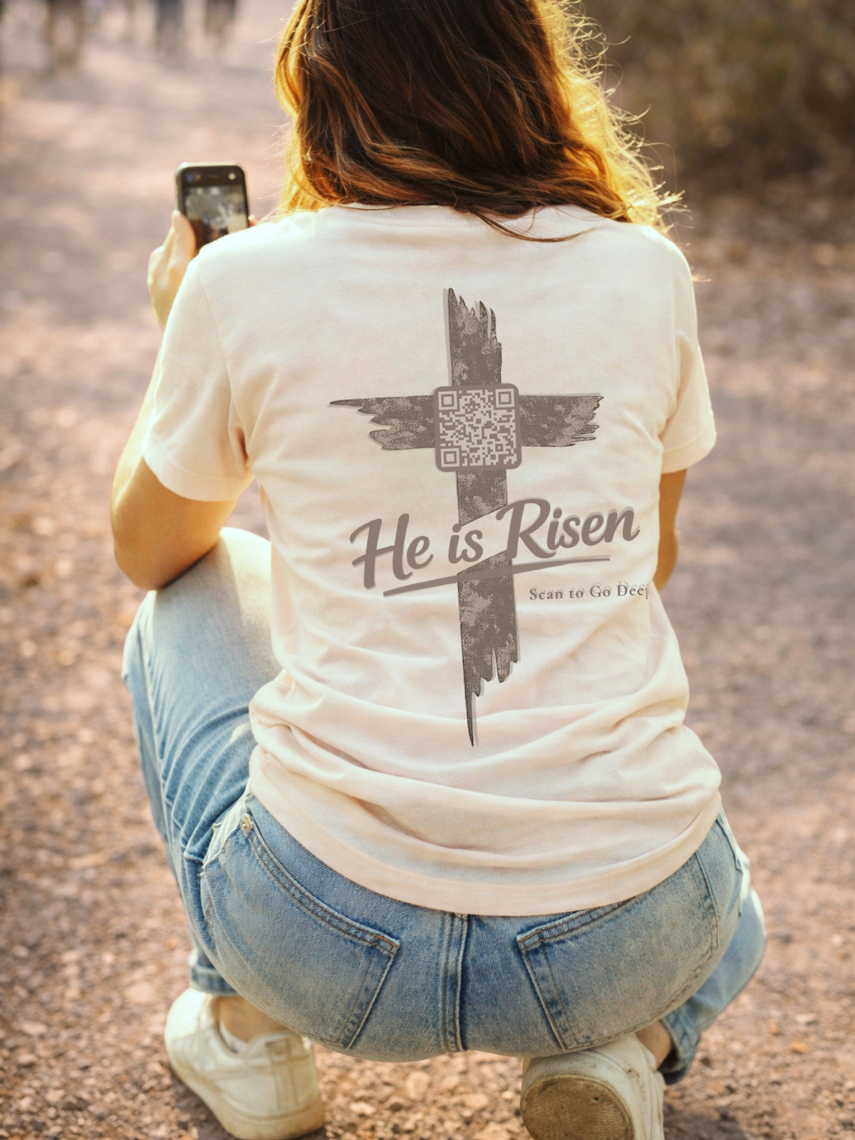 Person wearing a t-shirt with 'He is Risen' design outdoors